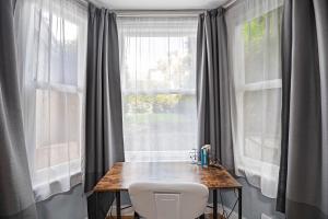 a table and a chair in front of a window at Pass the Keys Private Garden Apartment by Tulse Hill Station in London