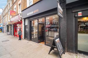a person standing outside of a store on a street at Pass the Keys Private Garden Apartment by Tulse Hill Station in London