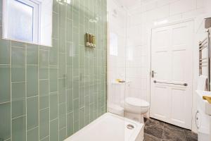 a bathroom with a toilet and a shower with green tiles at Pass the Keys Private Garden Apartment by Tulse Hill Station in London +37 photos