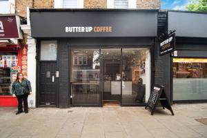 a woman standing in front of a coffee shop at Pass the Keys Private Garden Apartment by Tulse Hill Station in London