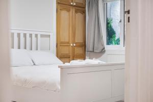 a white bedroom with a bed and a mirror at Pass the Keys Private Garden Apartment by Tulse Hill Station in London