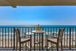 a table and chairs on a balcony with the beach at 1114 Boundless Awe by Atlantic Towers in Carolina Beach