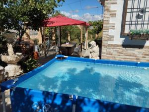 a blue swimming pool in a yard with a red umbrella at Loma Negra in Dúrcal