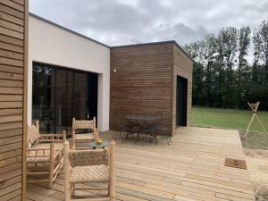 a patio with a table and chairs on a wooden deck at La cabane in Beaurepaire