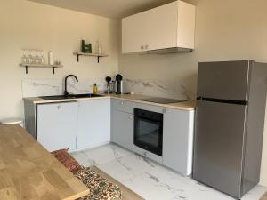 a kitchen with white cabinets and a stainless steel refrigerator at La cabane in Beaurepaire