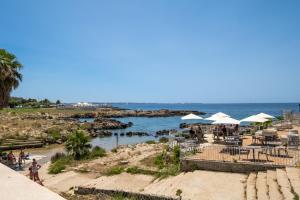 a beach with tables and umbrellas and the ocean at Gió home in Santa Maria al Bagno