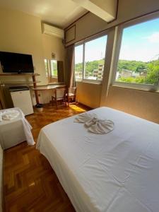 a bedroom with a white bed and a large window at Hotel Cataguases in Cataguases +44 photos