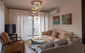 een woonkamer met een bank en een kroonluchter bij Limani Lux Apartments in Karpathos