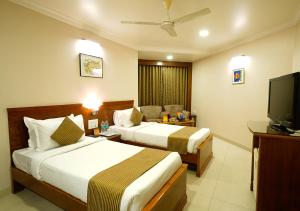 a hotel room with two beds and a flat screen tv at Hotel Mayura in Raipur