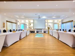 a conference room with white tables and chairs and a projection screen at La Villa Boutique Hotel in Accra
