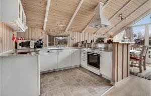 a kitchen with white cabinets and a large window at Holiday Home Birkemose In Dnmk in Skovby