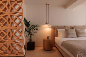 a bedroom with a bed and a potted plant at Asty Mykonos Hotel & Spa - World of One Hotel Group in Mikonos