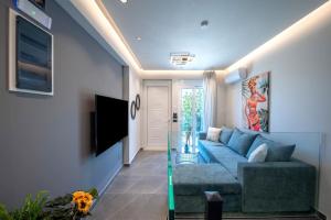 a living room with a blue couch and a tv at Santa Marina Luxury Apartments #1 with pool in Asgourou