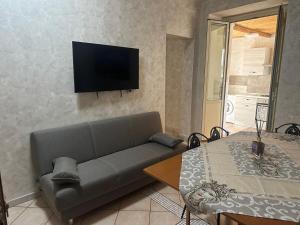 sala de estar con sofá y TV en la pared en Missori home 1, en Catania