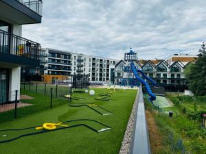 Un parque infantil con tobogán y tijeras en el césped. en Bel Mare 405, en Międzyzdroje