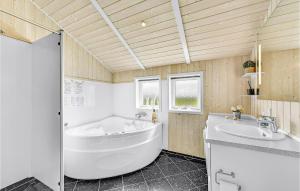 a bathroom with a large tub and a sink at Holiday Home Krogen Ringkøbing in Søndervig +19 photos