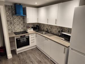 Una cocina con gabinetes blancos y un fregadero. en St Patrick Square Main Door, en Edimburgo