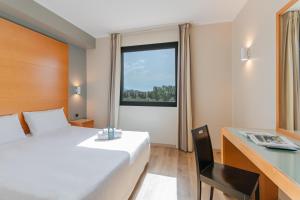 a bedroom with a bed and a desk and a window at B&B Hotel Pisa in Pisa