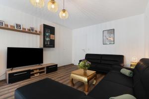 a living room with a black couch and a flat screen tv at Lopezan home and living in Hornberg