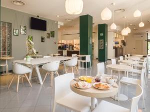 a restaurant with white tables and white chairs at B&B Hotel Faenza in Faenza