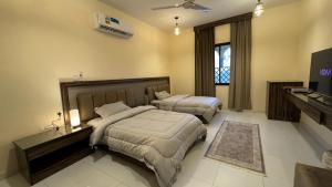 a bedroom with two beds and a television in it at Bait Al Hakem Guest Rooms in Salalah