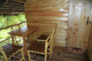 drewniany stół i 2 krzesła w kabinie w obiekcie Kumbuk Tree House w mieście Tissamaharama