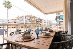 ein Holztisch mit Schüsseln und Tellern darauf auf einem Balkon in der Unterkunft rentafive - Luxury - Reformado - 2 min Gran Playa in Santa Pola
