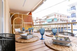 ein Holztisch mit blauen Gläsern auf einem Balkon in der Unterkunft rentafive - Luxury - Reformado - 2 min Gran Playa in Santa Pola