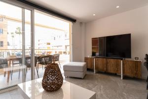 ein Wohnzimmer mit Flachbildfernseher und Tisch in der Unterkunft rentafive - Luxury - Reformado - 2 min Gran Playa in Santa Pola
