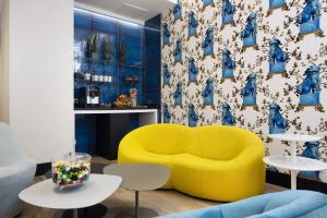 a living room with a yellow couch and two tables at Hotel Haussmann Saint Augustin in Paris