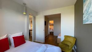 ein Schlafzimmer mit einem Bett mit roten Kissen und einem Stuhl in der Unterkunft Homency - Résidence Belvédère D5 in L'Alpe-d'Huez