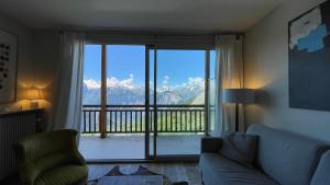 ein Wohnzimmer mit Sofa und Blick auf einen Balkon in der Unterkunft Homency - Résidence Belvédère D5 in L'Alpe-d'Huez