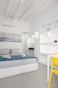 a white bedroom with a bed and a yellow chair at Mykonos Alley Stars - Anna Star in Mýkonos City