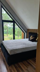 a bedroom with a large bed with a large window at Mazurskie Wzgórze Nad Jeziorem Isąg in Pelnik