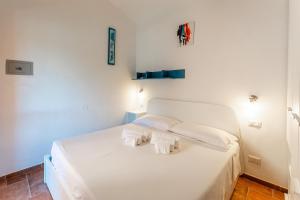 a white bed in a room with white walls at Villa Perdalonga, Vista Mare Sea View Tuerredda in Teulada