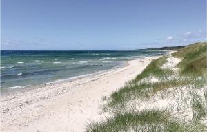 a beach with sand and the ocean on a sunny day at Four-Bedroom Holiday Home In Nexo in Vester Sømarken
