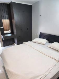 a bedroom with a large white bed with a black headboard at PND apartment 701 in Vientiane +10 photos