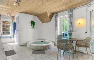 スナーヴィグにあるLovely Home In Ringkøbing With Saunaの浴槽とテーブルと椅子のあるバスルーム