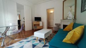 a living room with a blue couch and a tv at La Bulle du bois in Clamart