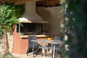 a table and chairs in front of an outdoor oven at Christina Villas, Steps to Sandy Beach, By ThinkVilla in Sfakaki