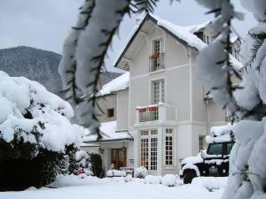 una casa bianca con alberi coperti di neve di fronte di Villa Portillon - charming fountain garden villa a Luchon