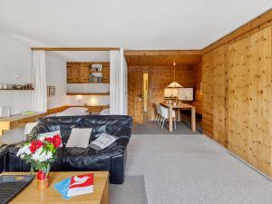 a living room with a black leather couch and a kitchen at Apartment Guardaval Apt 308 by Interhome in Davos