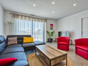 a living room with a blue couch and red chairs at Villa Les Alyzés by Interhome in Vensac