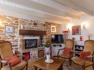 a living room with a stone fireplace and chairs at Holiday Home Les Hortensias by Interhome in Kerherneau