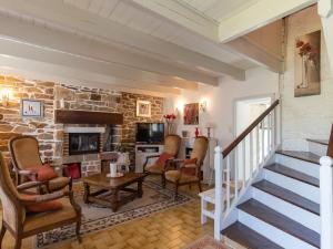 a living room with a stone fireplace and stairs at Holiday Home Les Hortensias by Interhome in Kerherneau