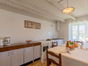 a kitchen with white cabinets and a table with a white table cloth at Holiday Home Les Hortensias by Interhome in Kerherneau +32 photos