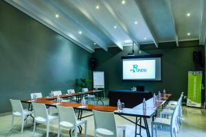 a conference room with tables and chairs and a screen at eBundu Lodge in White River