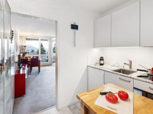 a kitchen with white cabinets and tomatoes on a cutting board at Apartment Parkareal - Utoring-13 by Interhome in Davos
