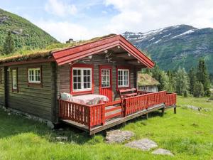 a log cabin in a field with mountains in the background at Chalet Fjellbris by Interhome in Holsen