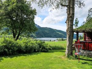 a basket in the grass next to a tree and a house at Chalet Haukedalspanorama by Interhome in Holsen